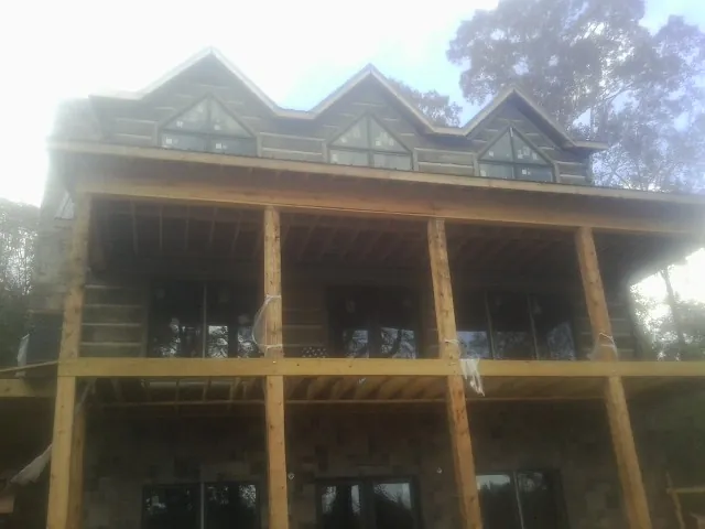 Dormers and porch framing on a large log home under construction — Roof Coating work by our crew in Central City